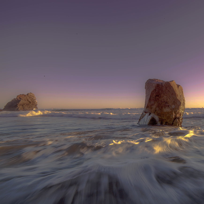 Dramatic Ocean Waves Crashing Against Rocks at Sunset