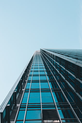 Low angle view of modern glass skyscraper against blue sky