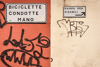 Italian street signs with graffiti on textured walls