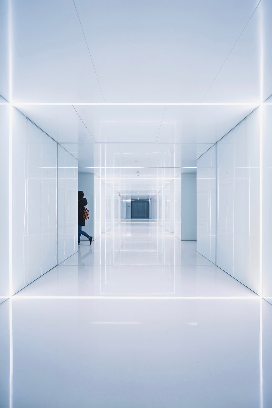 Futuristic white hallway with neon lights and lone figure