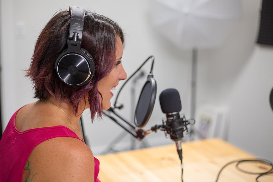 Woman with purple hair recording in a studio with microphone