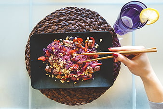 Top view of woman eating beet glass noodles with chopsticks