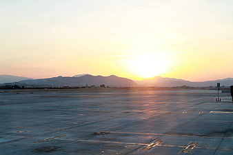 Sunset over airport tarmac with distant mountains