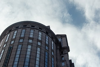 Low angle view of modern curved office building against cloudy sky
