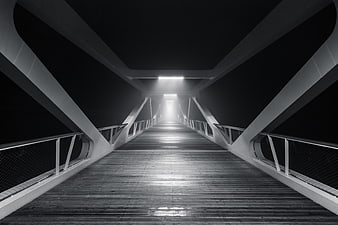Black and white perspective of a modern wooden bridge at night
