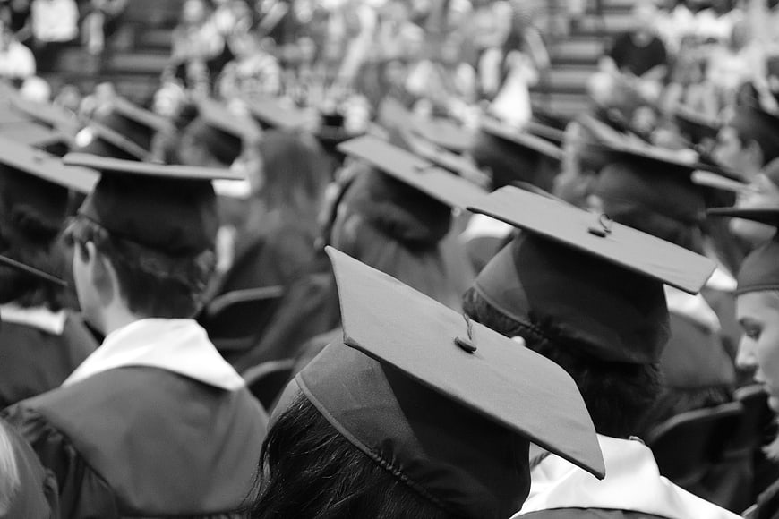 Black and white graduates in caps and gowns at ceremony