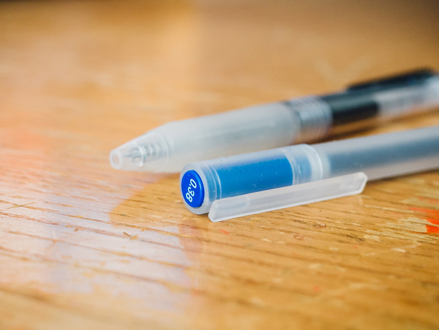 Close-up of blue and black gel pens on wooden desk