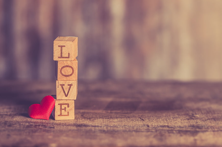 Wooden blocks spelling LOVE with red heart on rustic table