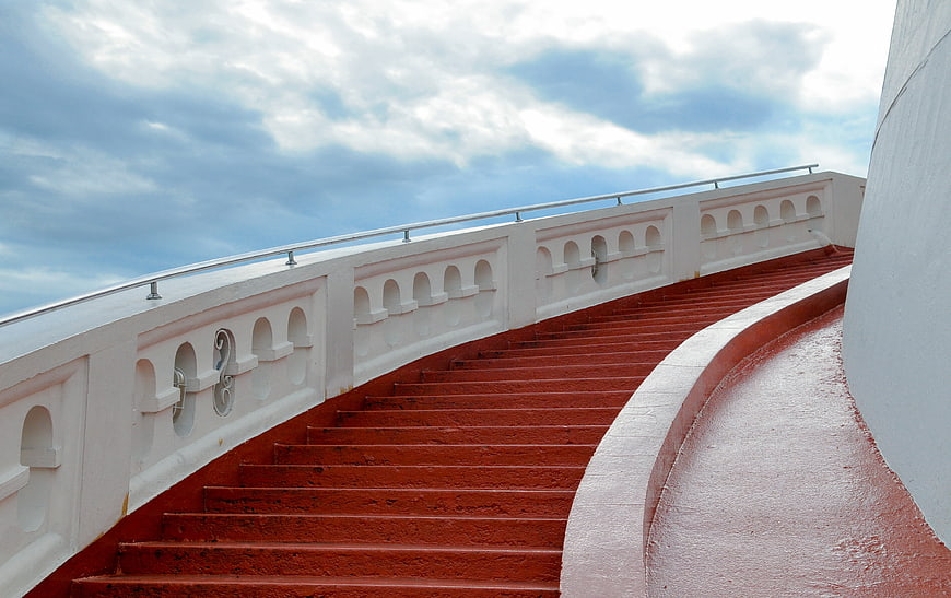 Red Curved Staircase With White Balustrade Against Blue Sky