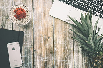 Flat lay workspace with laptop, pineapple, and smartphone on wood