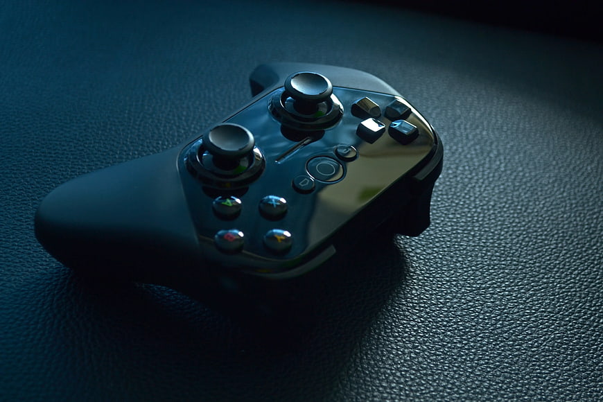 Black Wireless Game Controller on Textured Leather Surface