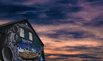Street Art Mural on Brick Wall Against Dramatic Sunset Sky