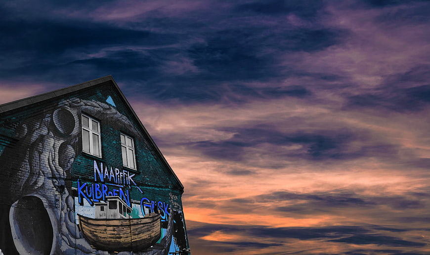 Street Art Mural on Brick Wall Against Dramatic Sunset Sky
