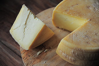 Fresh wedge of yellow cheese on rustic wooden board