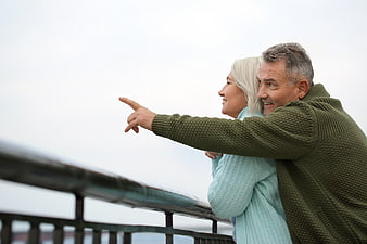 Happy Senior Couple Pointing at Scenic View from Balcony