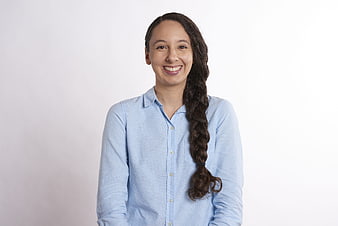 Smiling woman with long braid in light blue shirt on white background