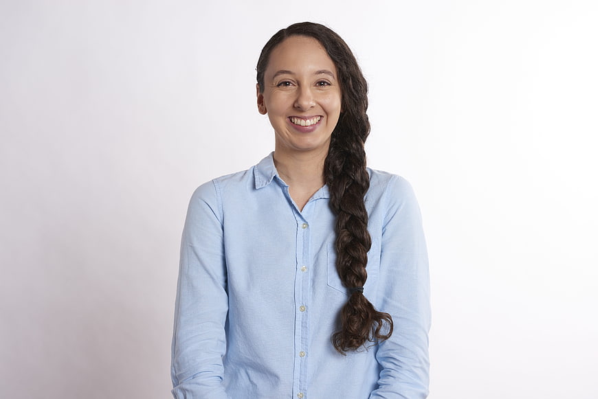 Smiling woman with long braid in light blue shirt on white background