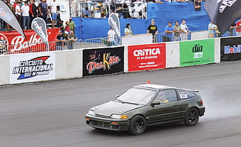 Green Honda Civic drifting on race track with smoke