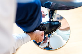 Man tying black leather dress shoe laces close up