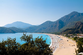 Aerial View of Long Sandy Beach with Mountains and Blue Sea
