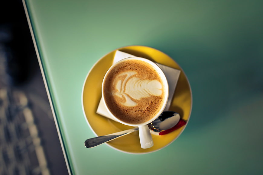 Top View Cappuccino with Latte Art on Yellow Saucer