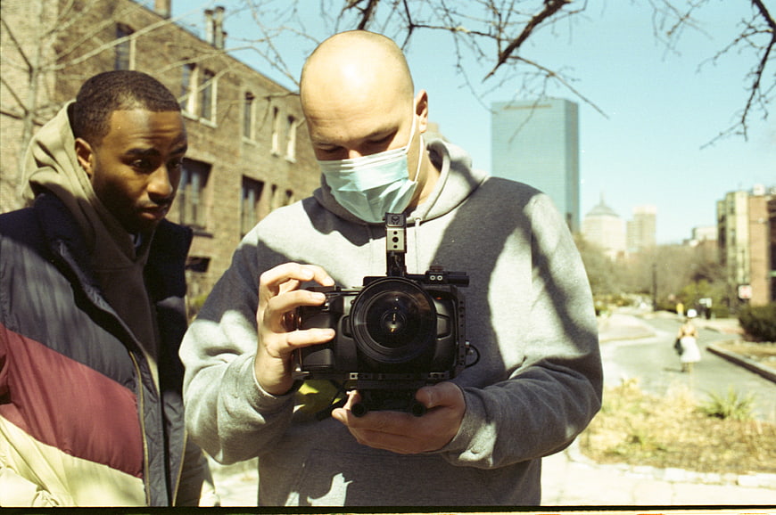 Two Men Reviewing Camera Footage Outdoors in Urban Park