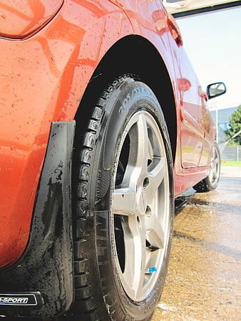 Close-up of wet red car wheel and tire at car wash