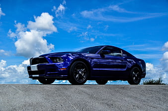 Blue Ford Mustang GT Muscle Car Parked On Concrete Under Blue Sky