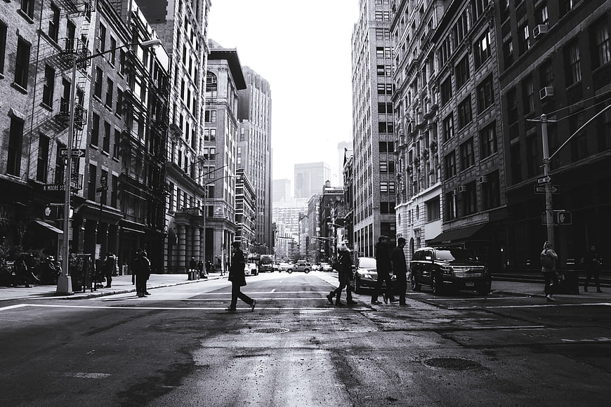 Black and white urban street scene with pedestrians crossing