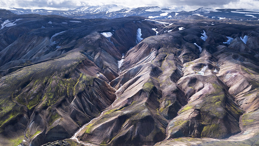 Aerial view of rugged volcanic mountains with snow patches in Iceland