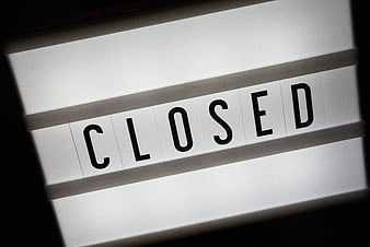 Close-up of a white flip sign displaying the word CLOSED