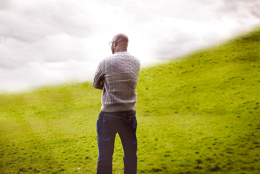 Man in Sweater Standing on Green Hillside