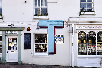 White storefronts with large blue letter T and street signs