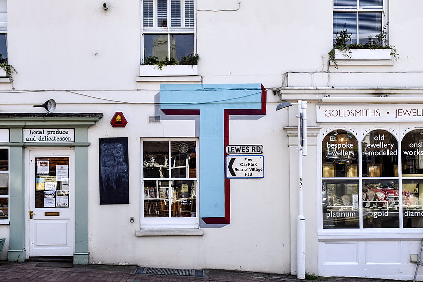 White storefronts with large blue letter T and street signs