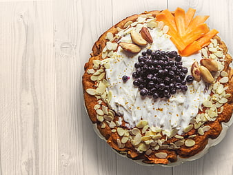 Overhead view of carrot cake with cream cheese frosting and fruit toppings
