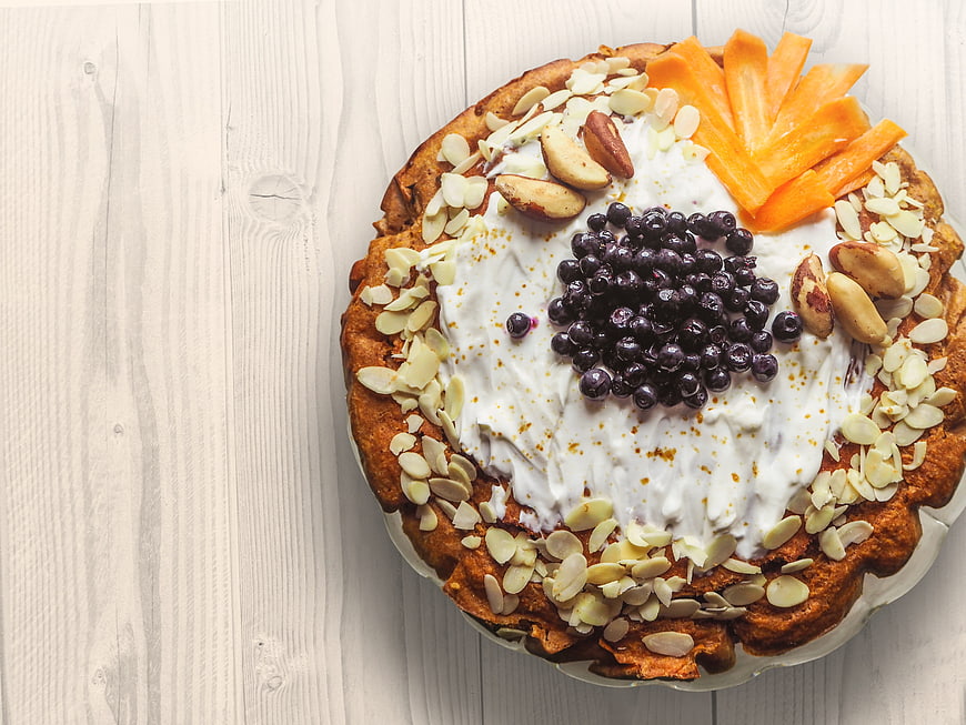 Overhead view of carrot cake with cream cheese frosting and fruit toppings