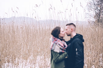 Blurred couple kissing in tall dry grass field
