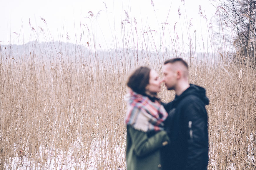 Blurred couple kissing in tall dry grass field