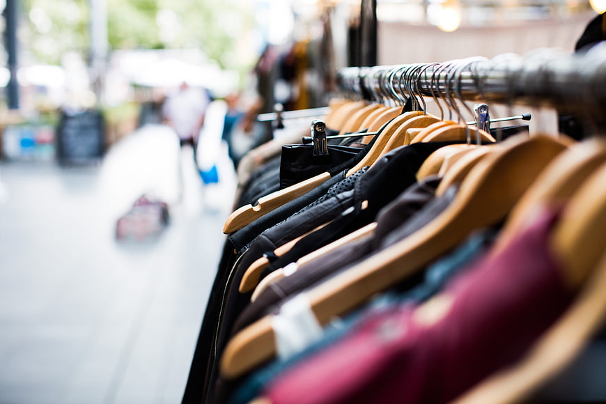 Clothing on wooden hangers in a boutique shop
