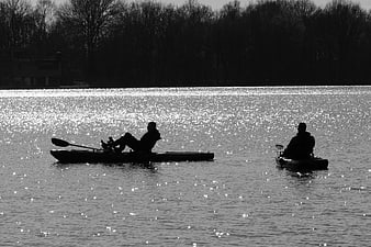 Silhouettes of Two Kayakers on Sparkling Lake Water