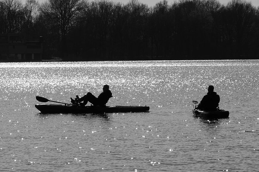 Silhouettes of Two Kayakers on Sparkling Lake Water