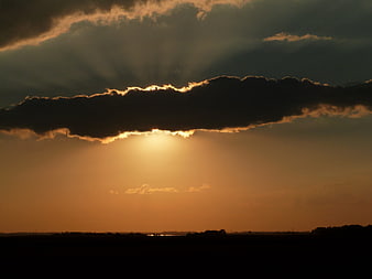 Dramatic sunset with sun rays breaking through dark clouds