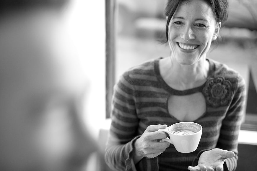 Smiling woman holding coffee cup in black and white