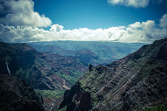 Dramatic lush green mountain valley with deep canyons and clouds