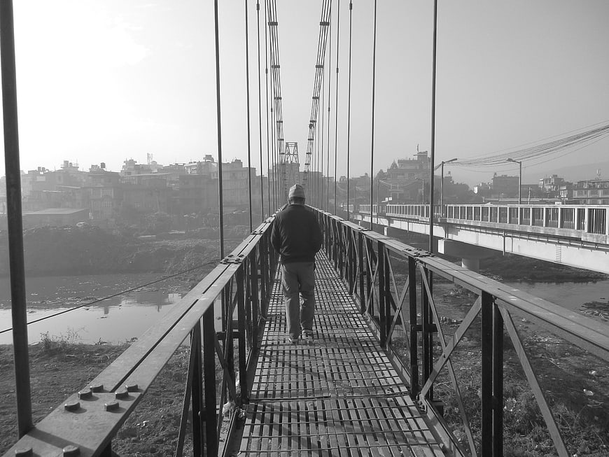 Man walking away on metal suspension bridge