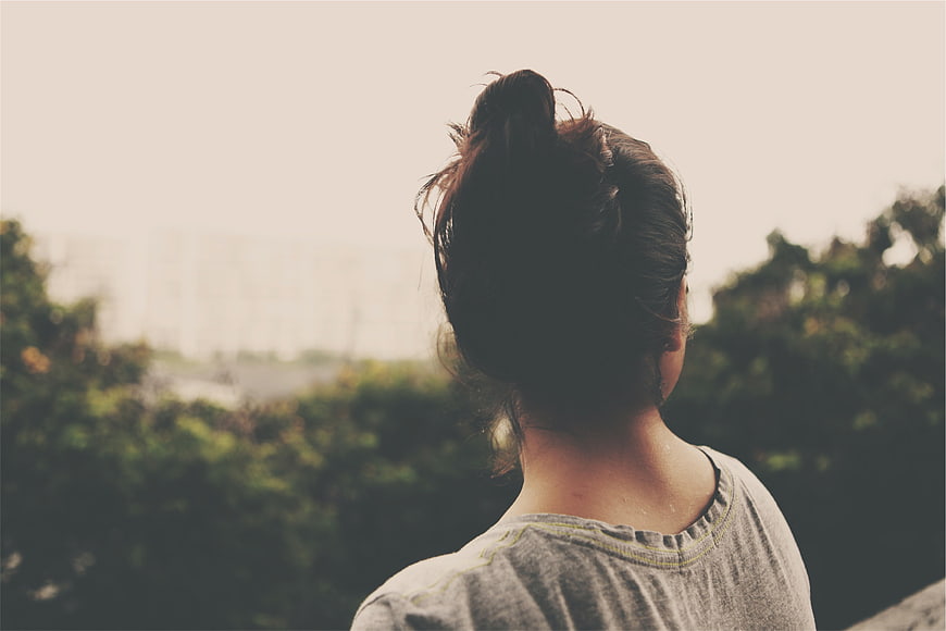 Woman with Bun Looking Out at City View