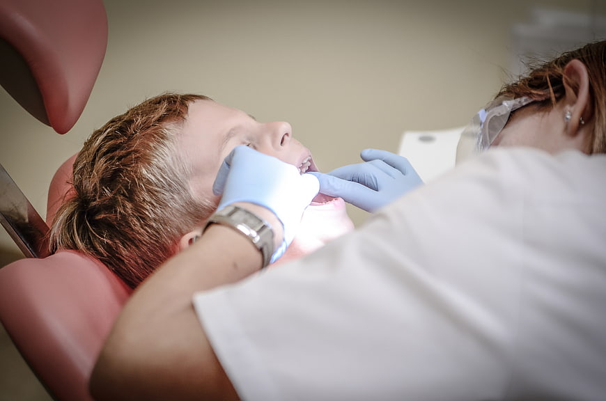 Dentist examining young boy's teeth in clinic