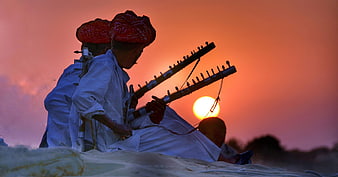 Indian musicians playing traditional instruments at sunset in Rajasthan