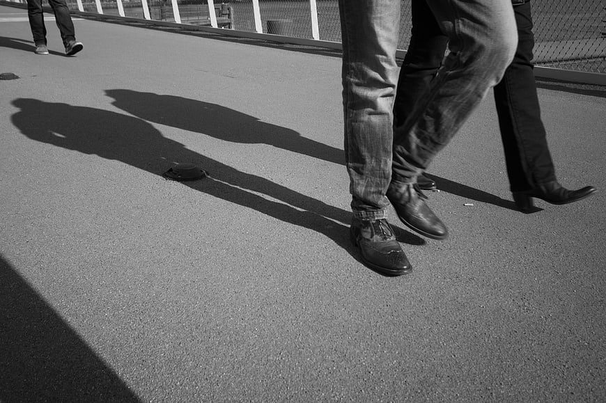 Black and white photo of walking feet and long shadows