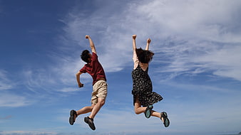 Happy couple jumping in the air against blue sky